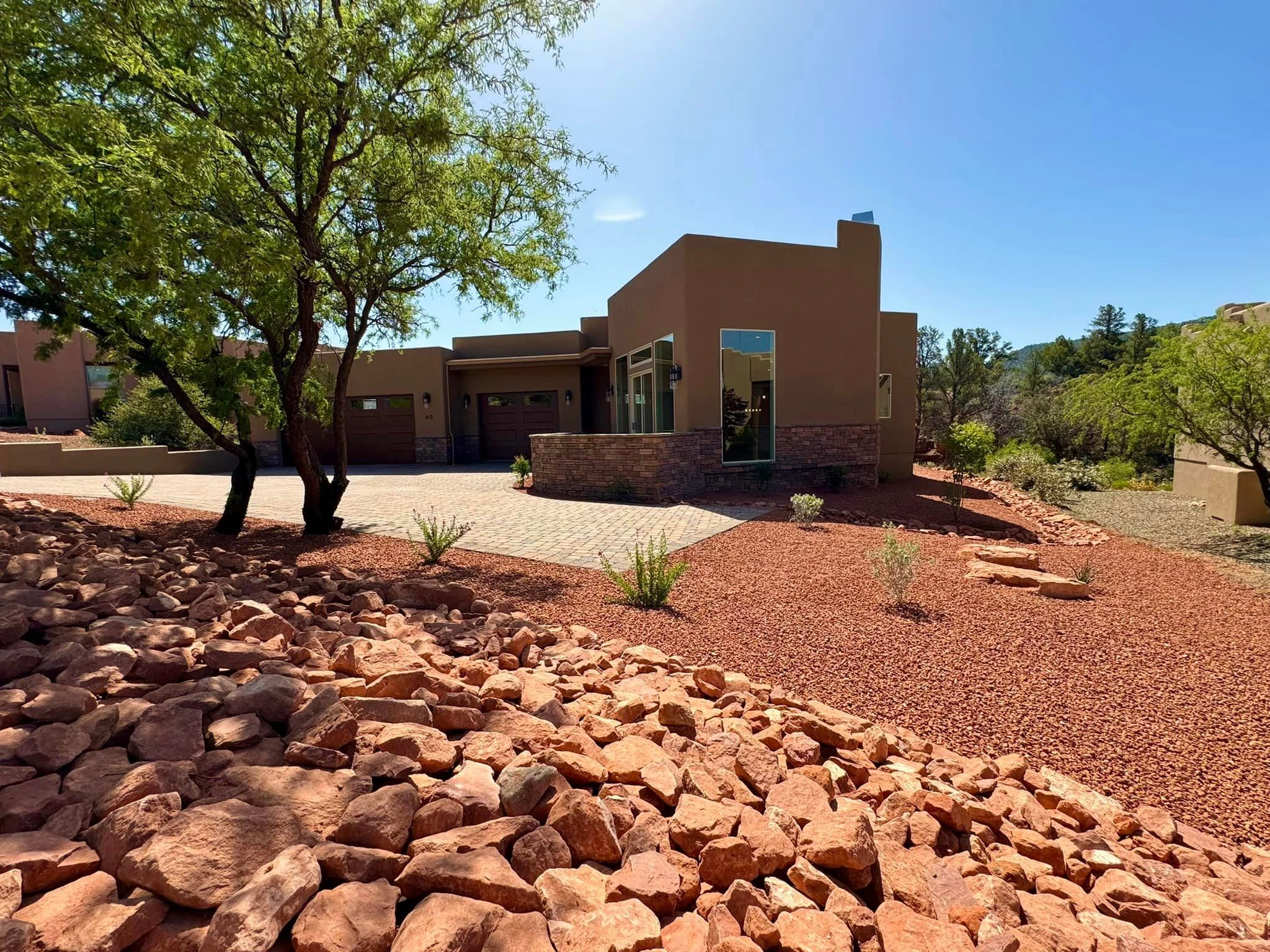Brown stucco house with stone detail work, surrounded by beautiful rock landscaping